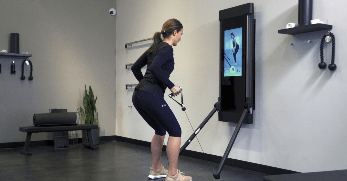 woman using Tonal gym equipment in her living room